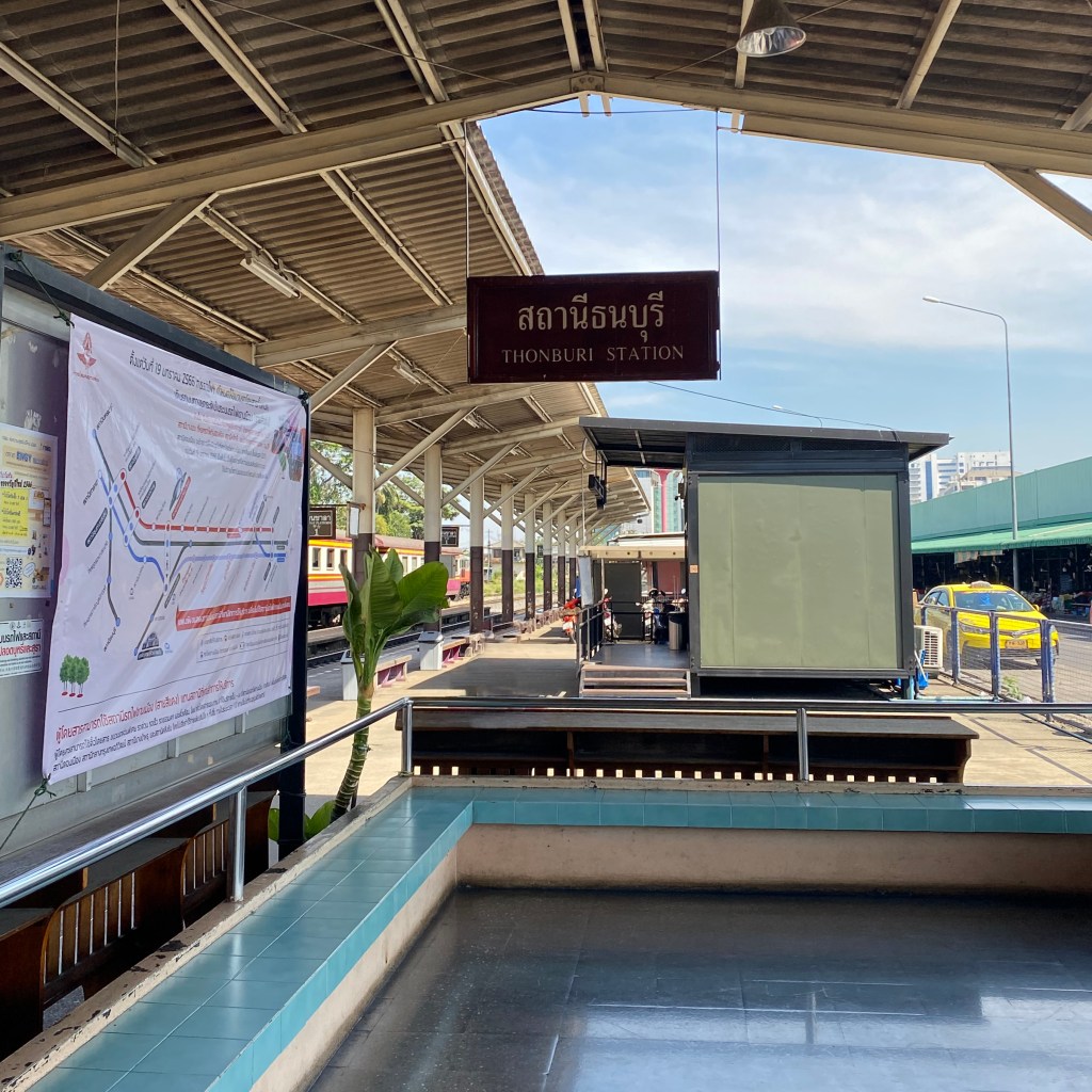 Thonburi railway station seating area showing the train track on the left and the road on the right. 