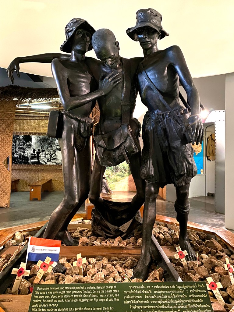 Image showing a sculpture inside the museum of three prisoners of war. The man in the middle is being held up by the other two.
