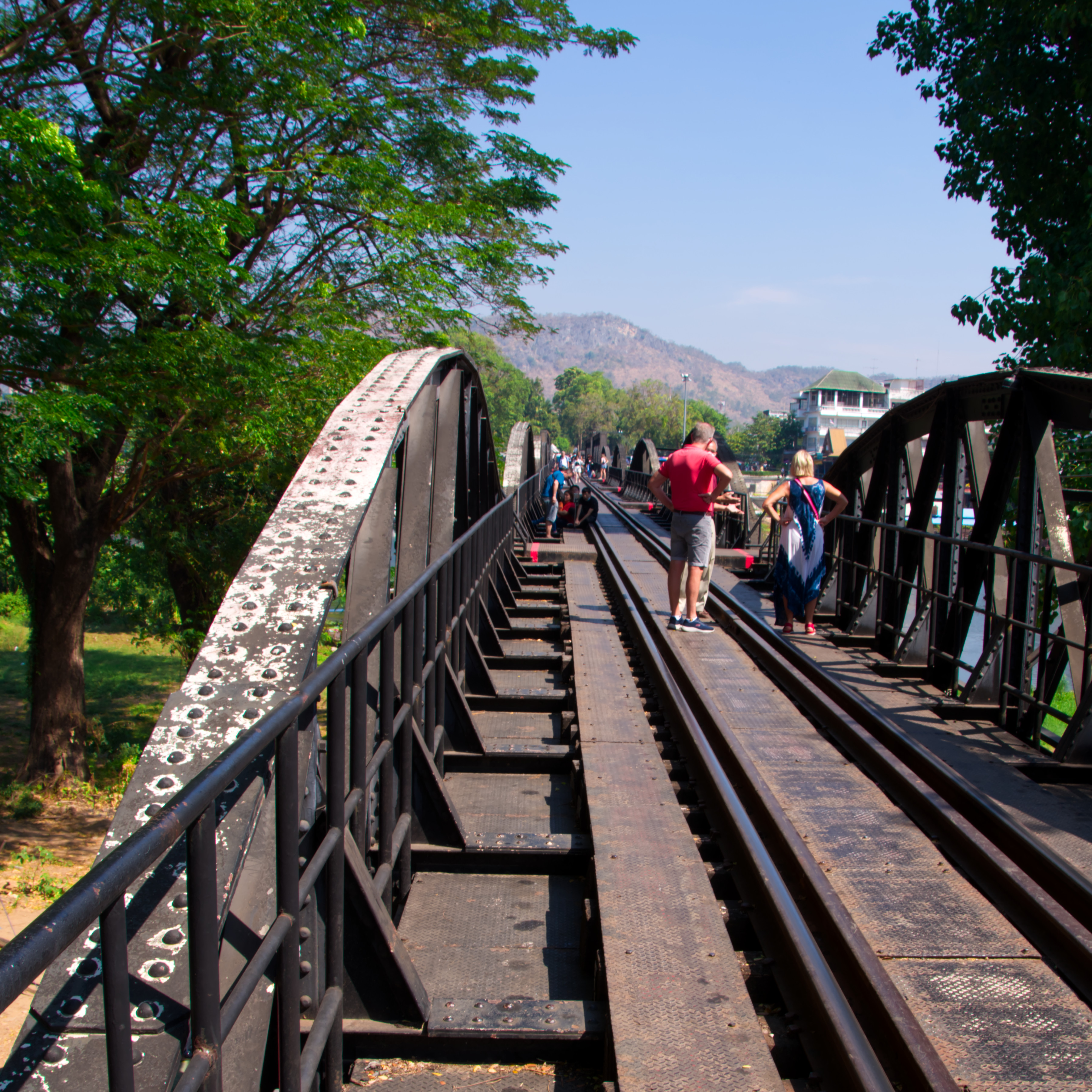 People standing chatting on the train tracks on the Bridge on the River Kwai